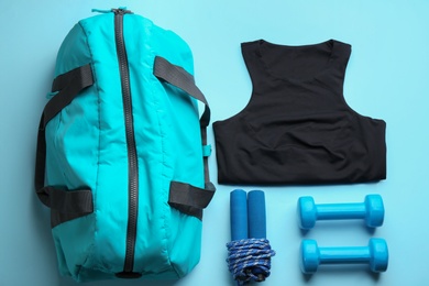 Photo of Flat lay composition with gym bag and sports items on light blue background