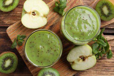 Photo of Delicious kiwi smoothie and fresh fruits on wooden table, flat lay