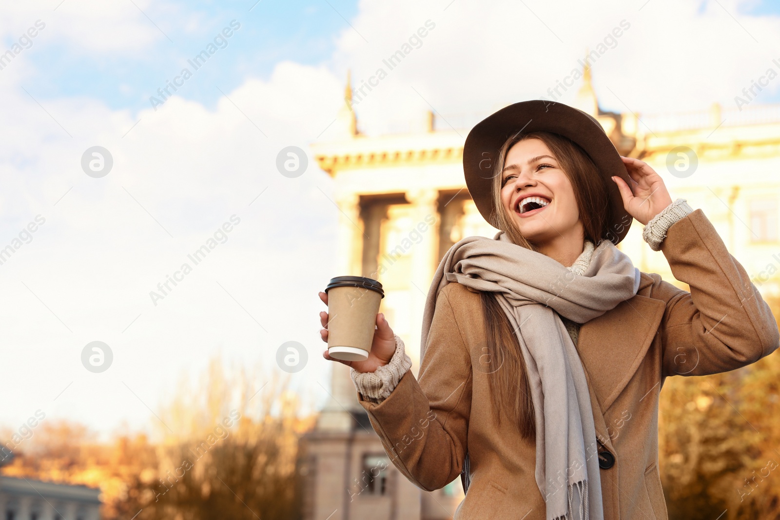 Photo of Young woman with cup of coffee on city street in morning