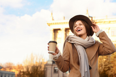 Photo of Young woman with cup of coffee on city street in morning