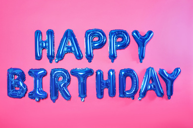 Phrase HAPPY BIRTHDAY made of blue foil balloon letters on pink background