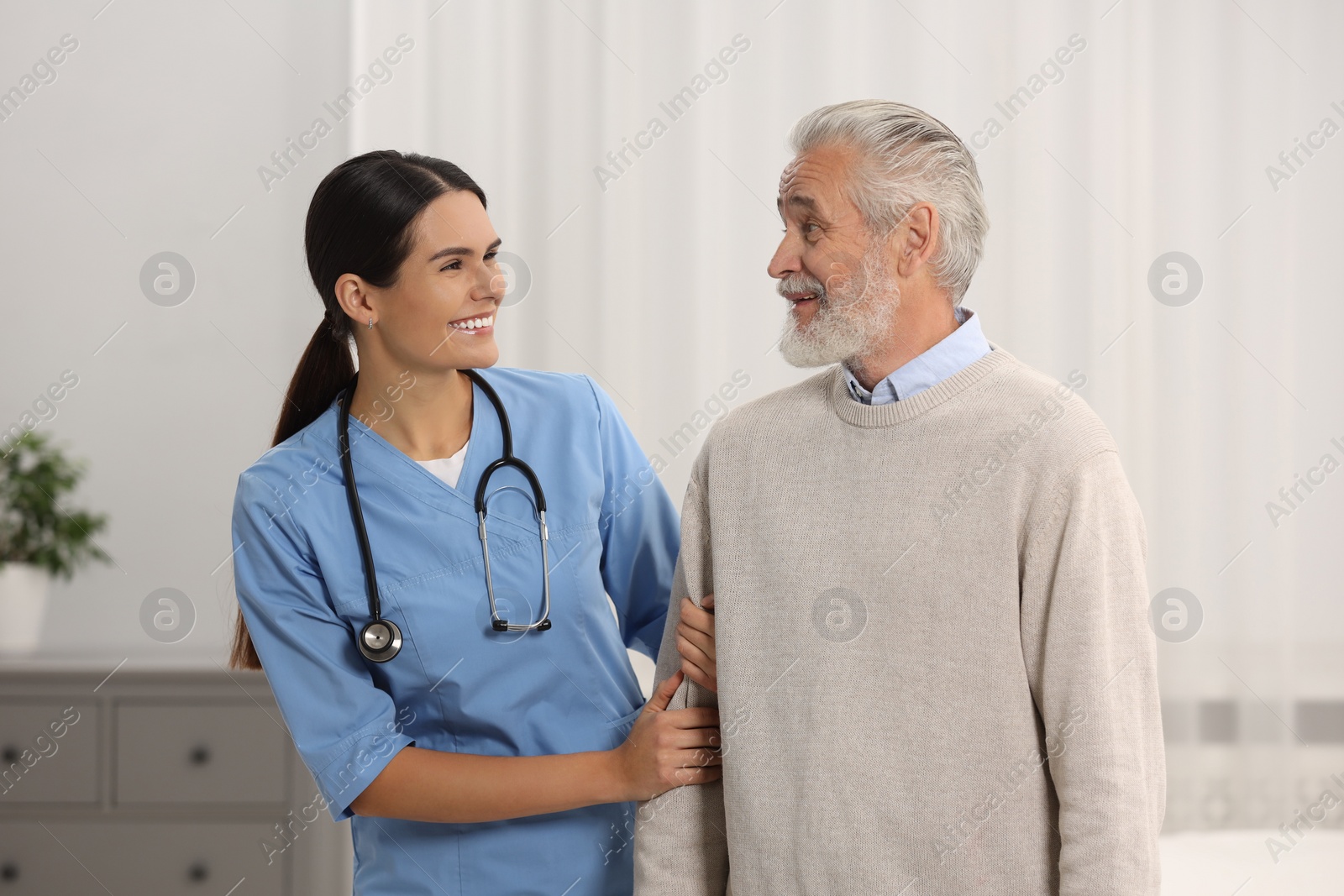 Photo of Health care and support. Smiling nurse with elderly patient in hospital