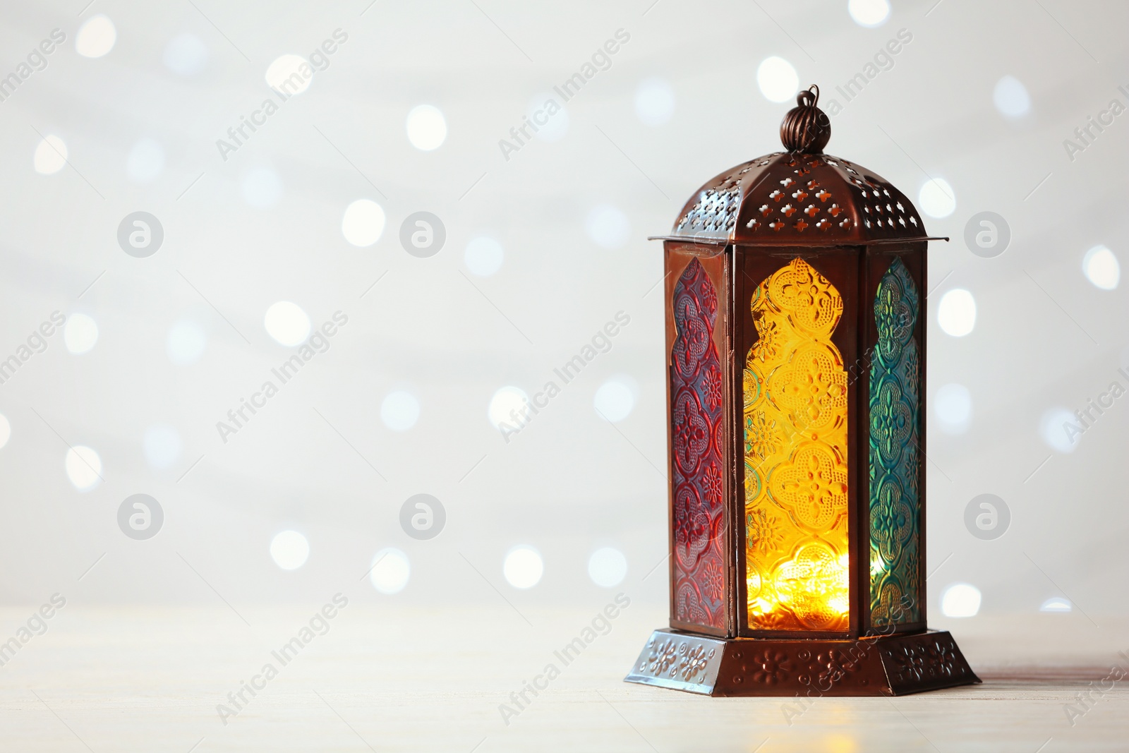 Photo of Muslim lamp Fanus and space for design on blurred lights background