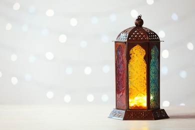 Photo of Muslim lamp Fanus and space for design on blurred lights background