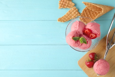 Delicious strawberry ice cream on blue wooden table, flat lay. Space for text