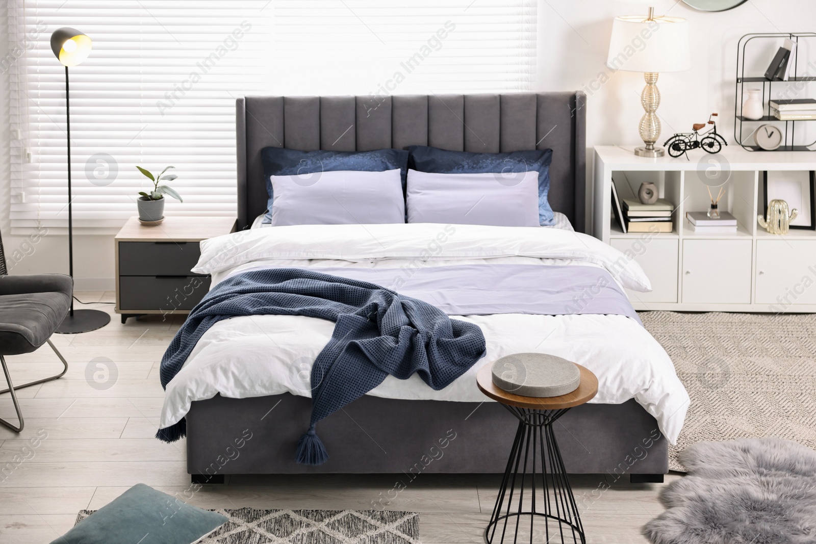 Photo of Bright plaid on bed in stylish bedroom. Interior design