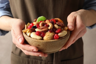 Young woman holding bowl with different dried fruits and nuts, closeup