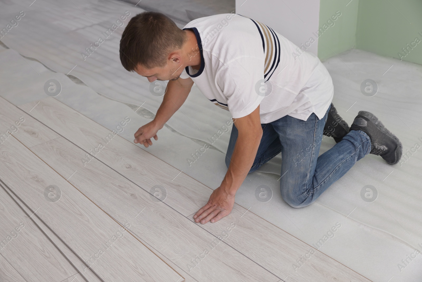 Photo of Man installing new laminate flooring in room