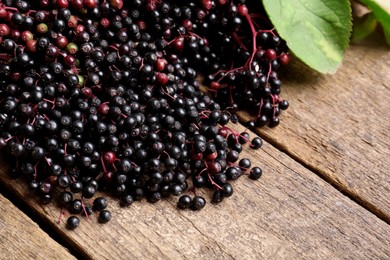 Photo of Pile of tasty elderberries (Sambucus) on wooden table, space for text