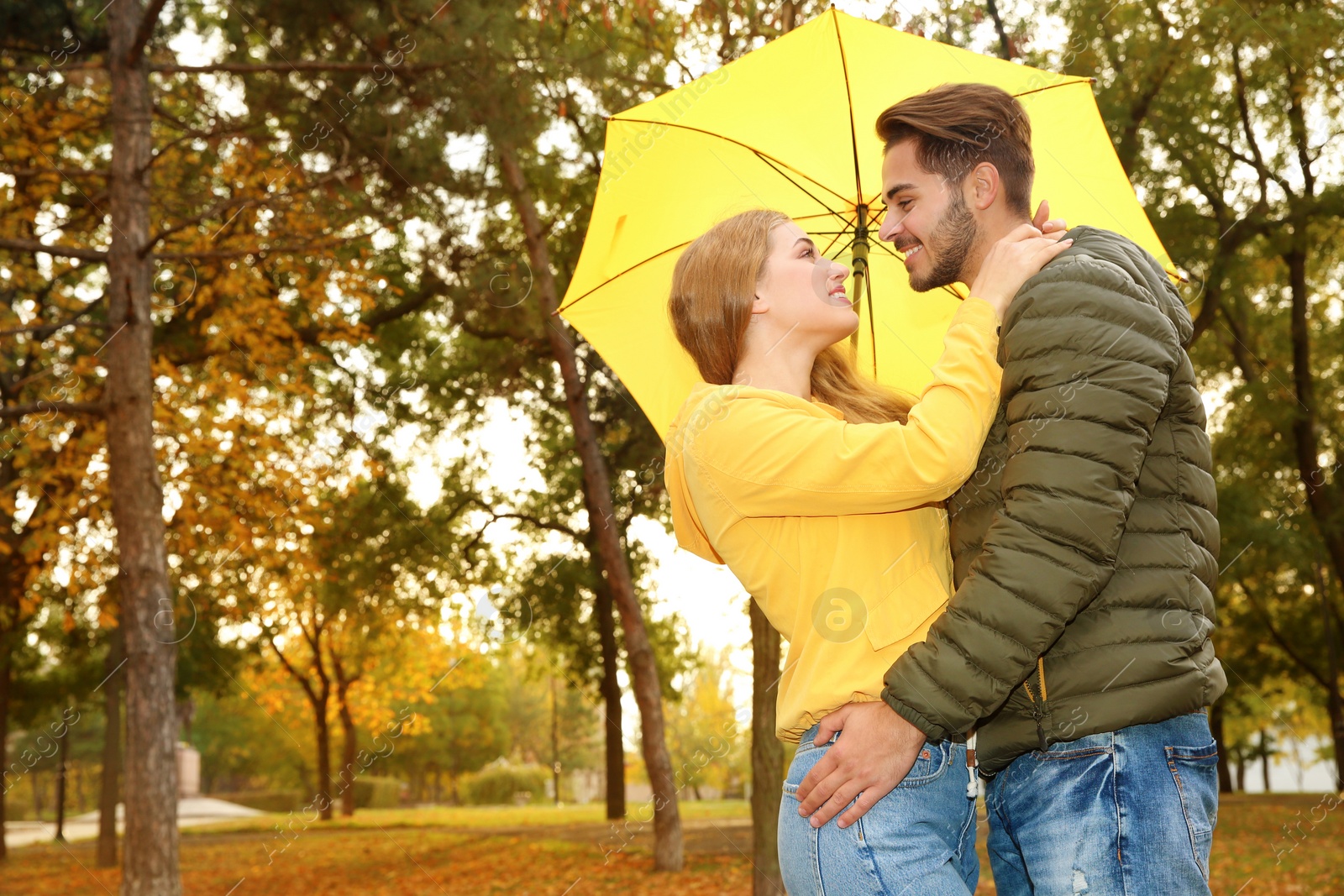 Photo of Happy couple with colorful umbrella in park. Space for text