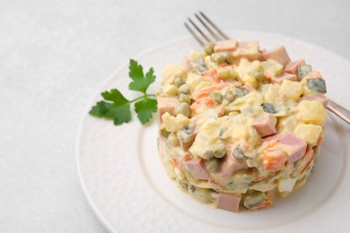 Photo of Tasty Olivier salad with boiled sausage and fork on light table, closeup. Space for text