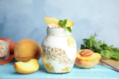 Photo of Tasty peach dessert with yogurt and granola on light blue wooden table