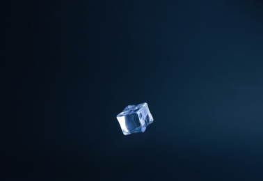 Photo of Crystal clear ice cube on dark blue background