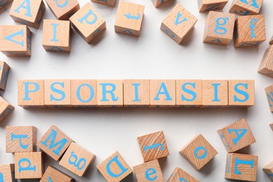 Word Psoriasis made of wooden cubes with letters on white table, flat lay