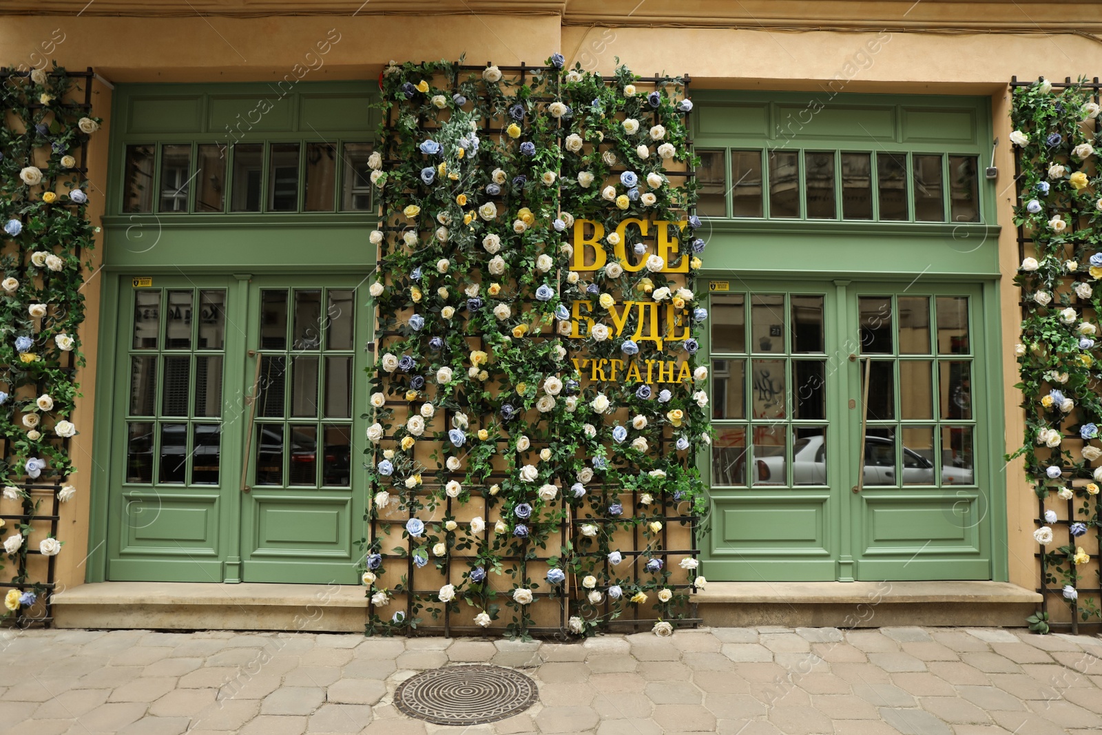 Photo of LVIV, UKRAINE - MAY, 27, 2022: Inscription Everything will be Ukraine written in ukrainian and arranged with flowers near entrance of building