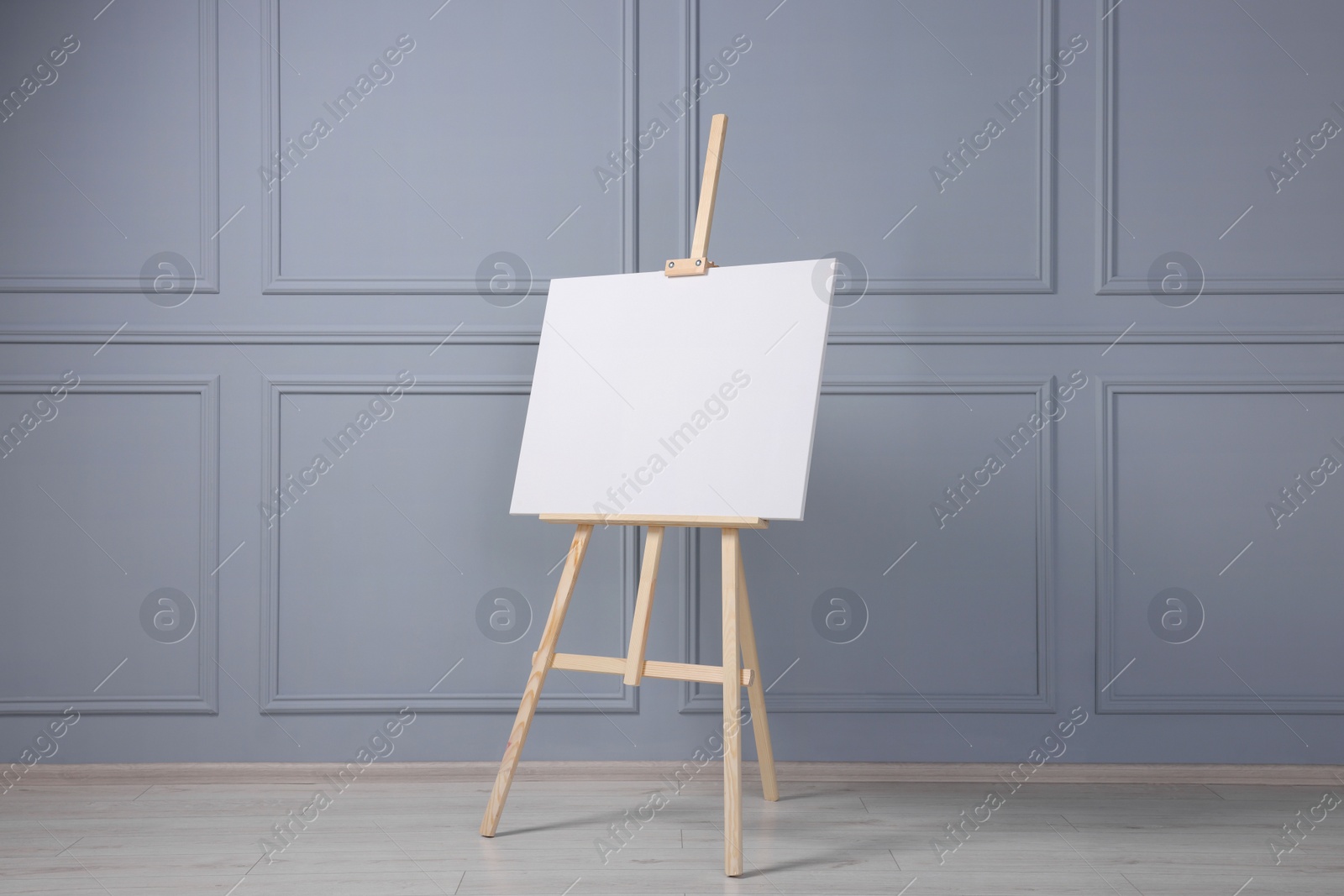 Photo of Wooden easel with blank canvas near grey wall indoors