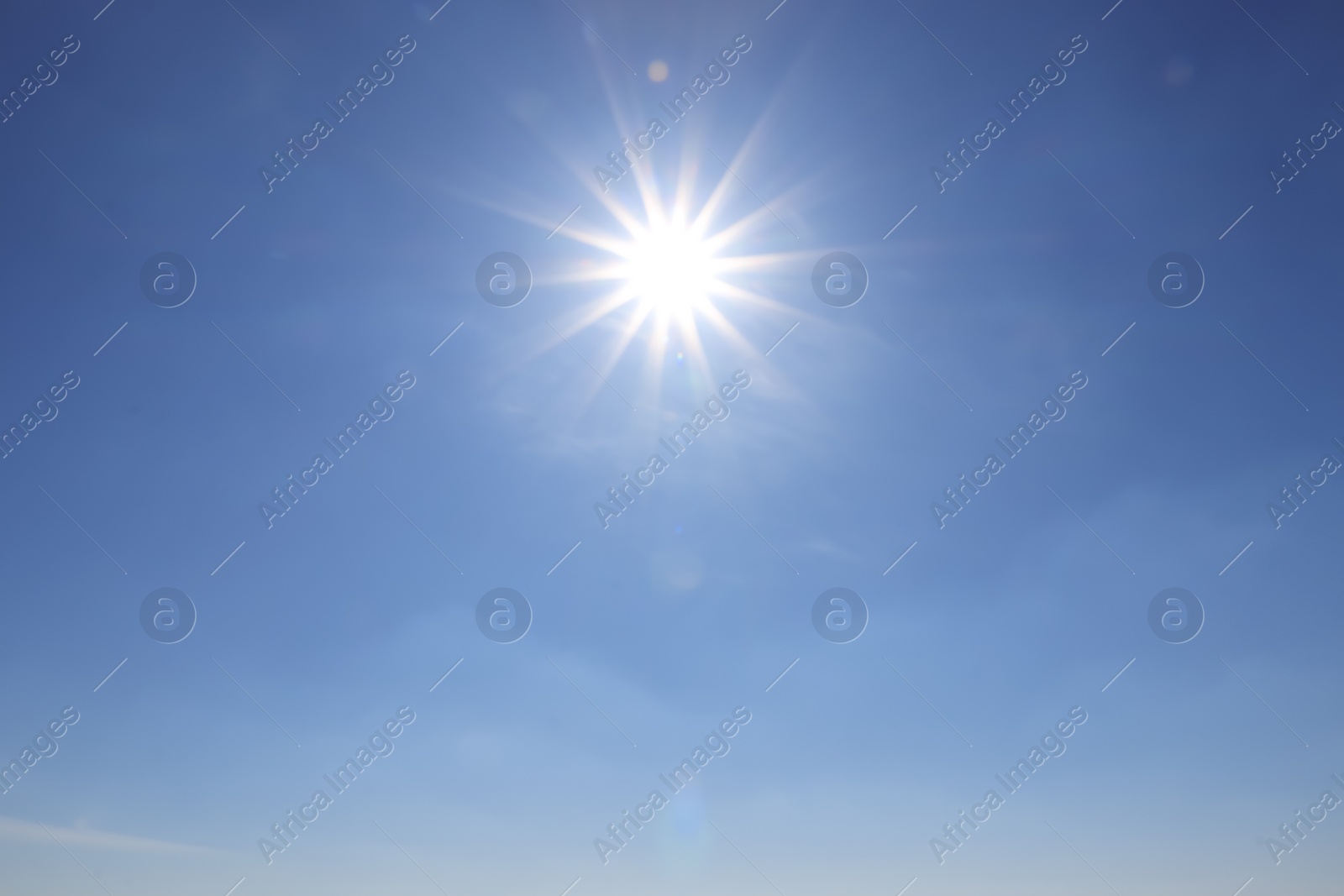 Photo of Bright sun in blue sky. Halo effect