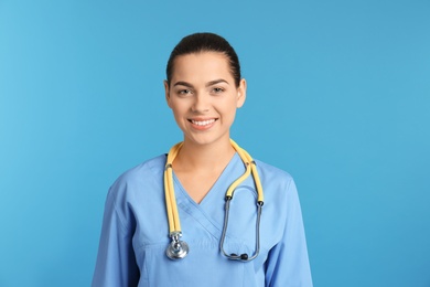 Portrait of young medical assistant with stethoscope on color background