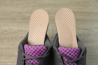 Orthopedic insoles in shoes on floor, closeup