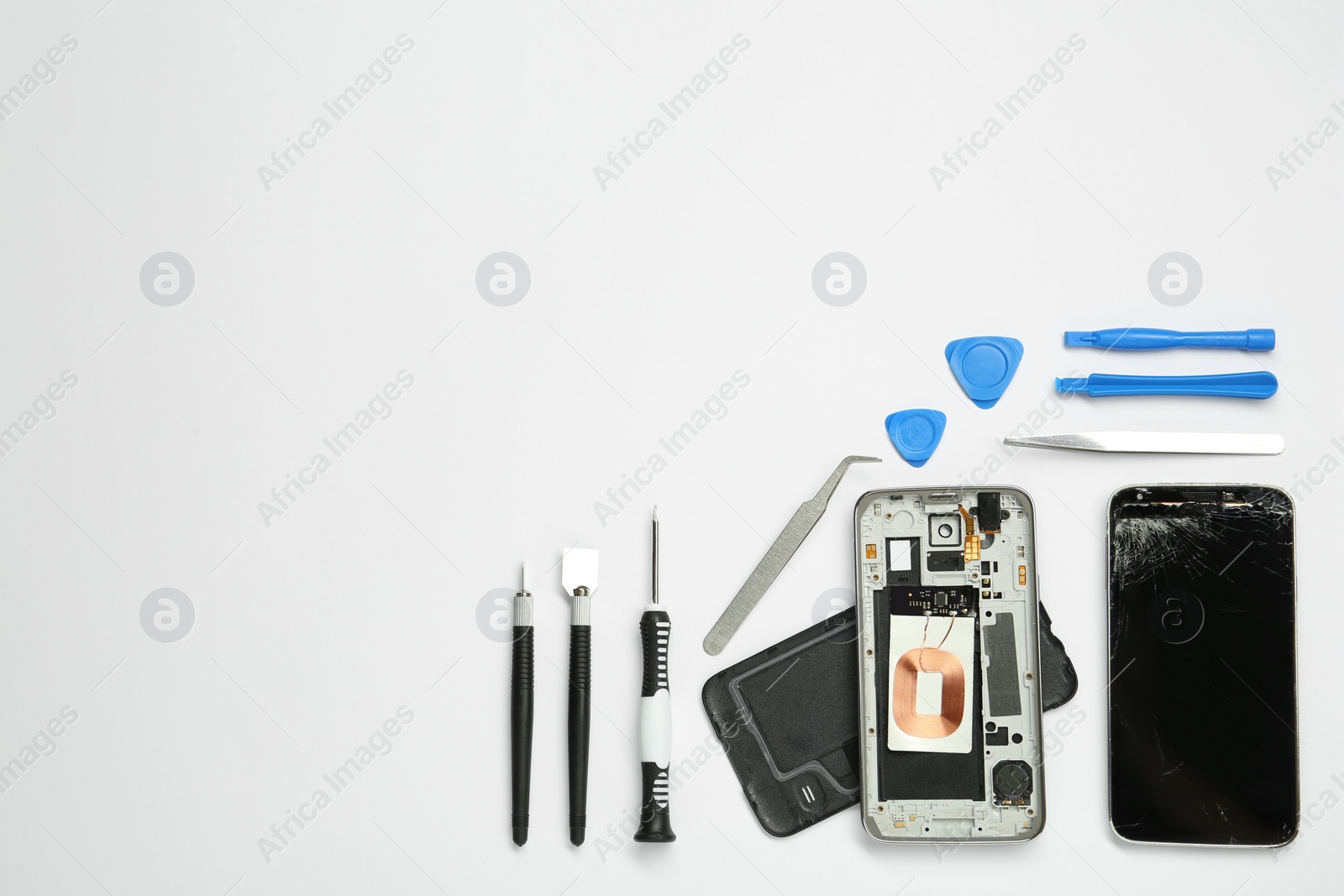 Photo of Damaged smartphone and repair tool set on white background, flat lay. Space for text