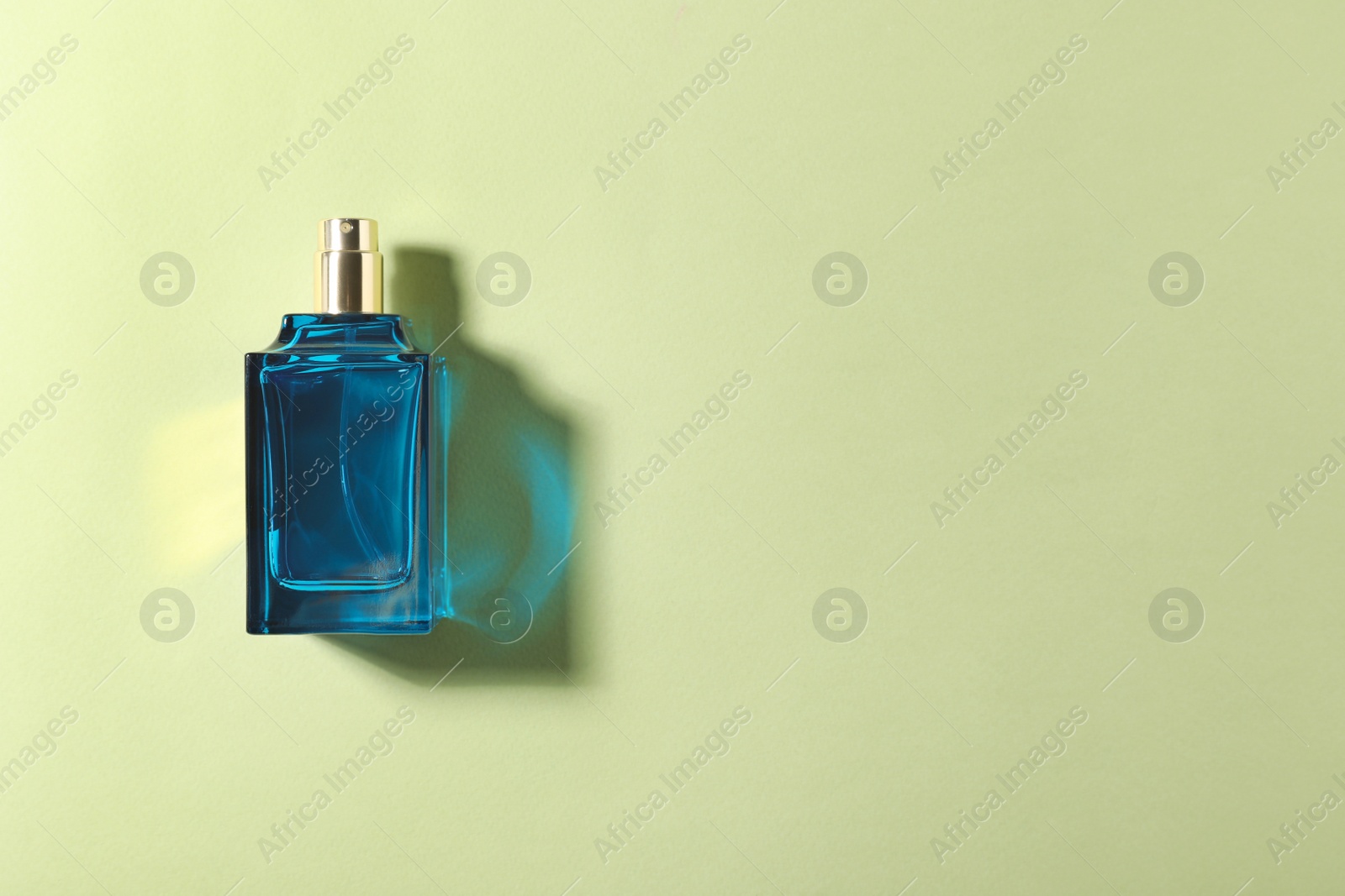 Photo of Bottle of perfume on color background, top view