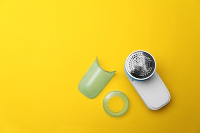 Photo of Modern fabric shaver and parts on yellow background, flat lay. Space for text