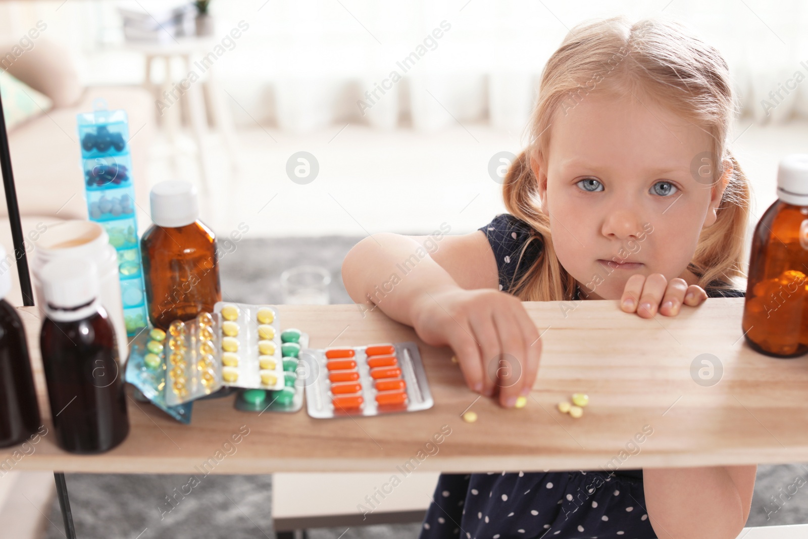 Photo of Little child taking pills from shelf at home. Danger of medicament intoxication