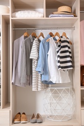 Photo of Collection of stylish clothes and shoes in large wardrobe closet