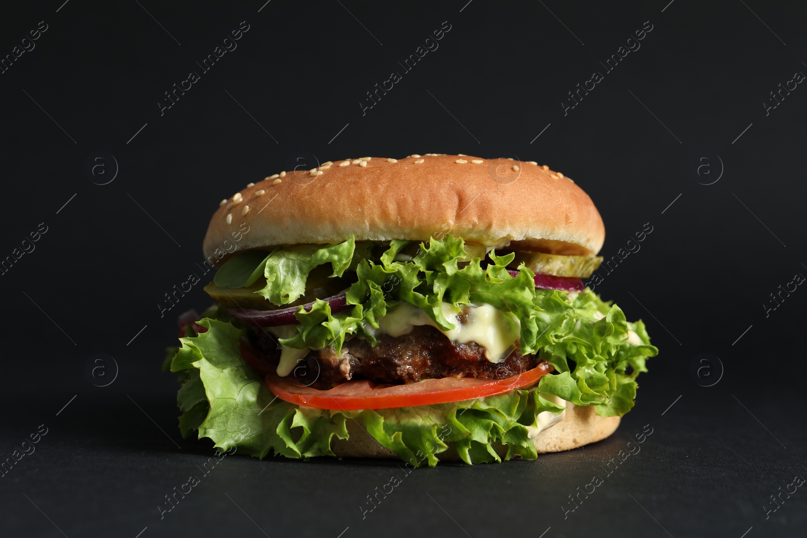 Photo of Delicious burger with beef patty and lettuce on black background