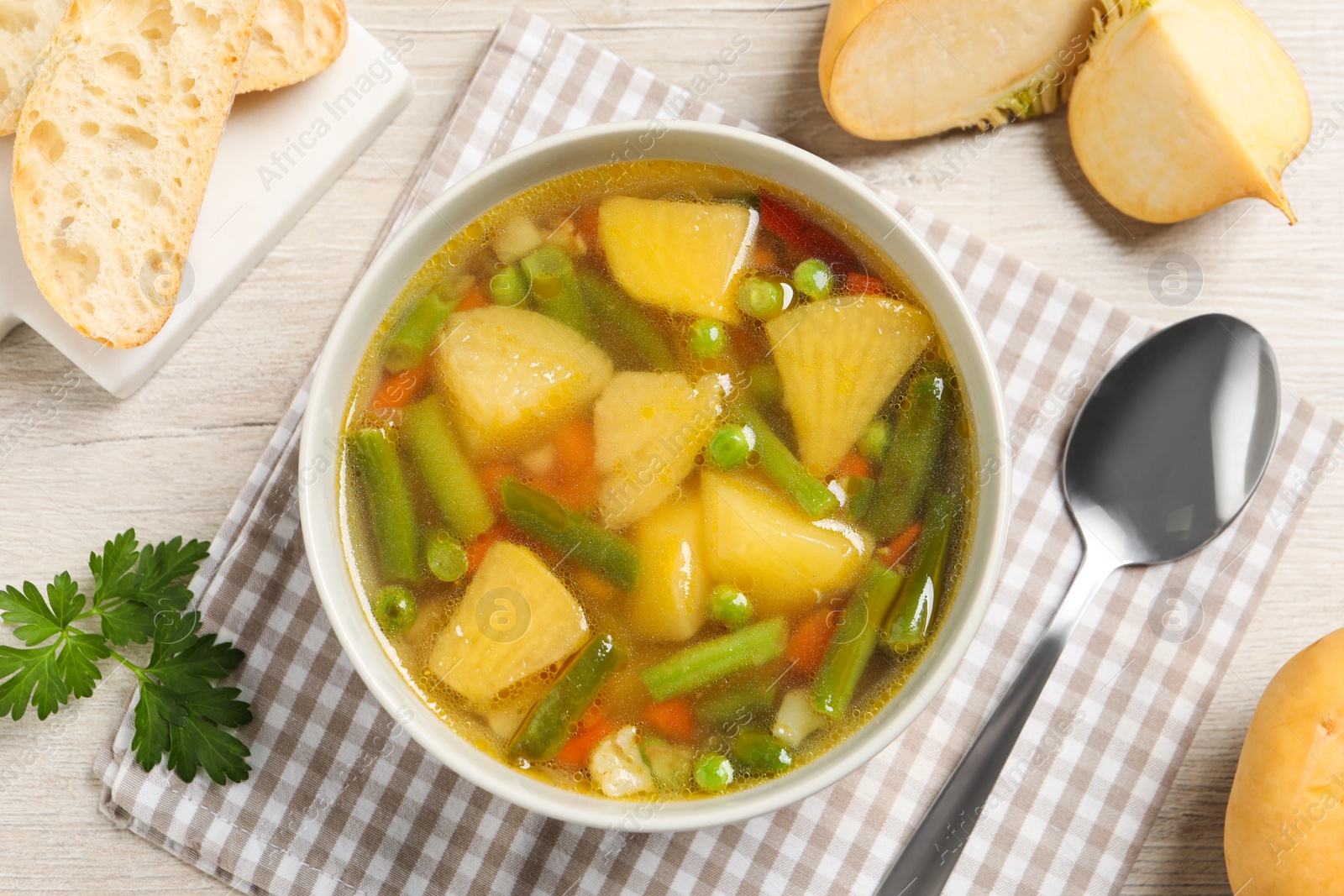 Photo of Bowl of delicious turnip soup served on wooden table, flat lay