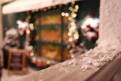 Photo of Wooden railing with snow on blurred background, closeup. Christmas celebration