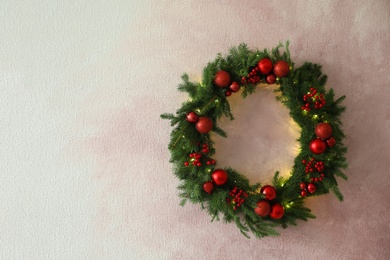 Photo of Beautiful Christmas wreath with festive decor on light pink wall, space for text