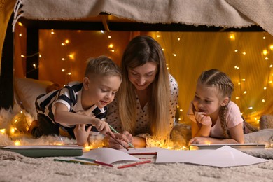 Photo of Mother and her children drawing in play tent at home