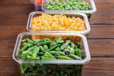 Photo of Different tasty frozen vegetables on wooden table