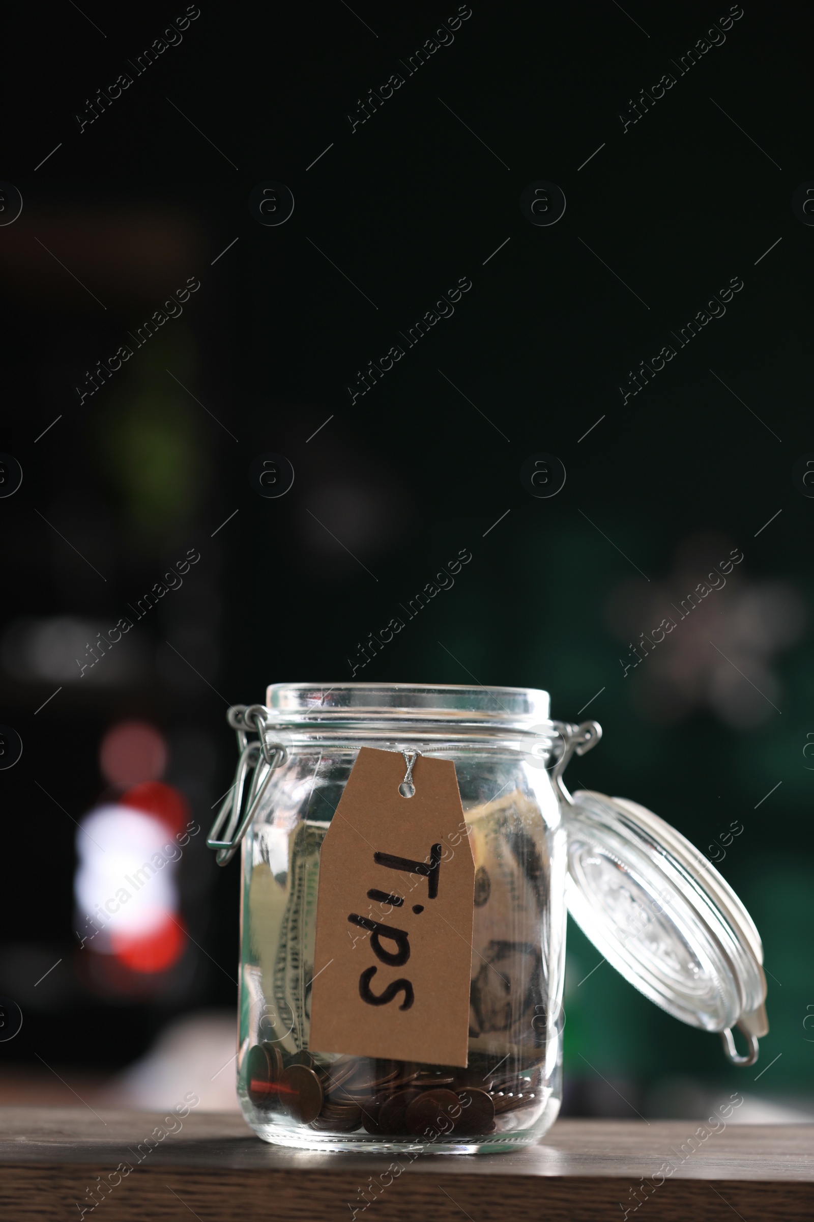 Photo of Glass jar with tips on wooden table indoors
