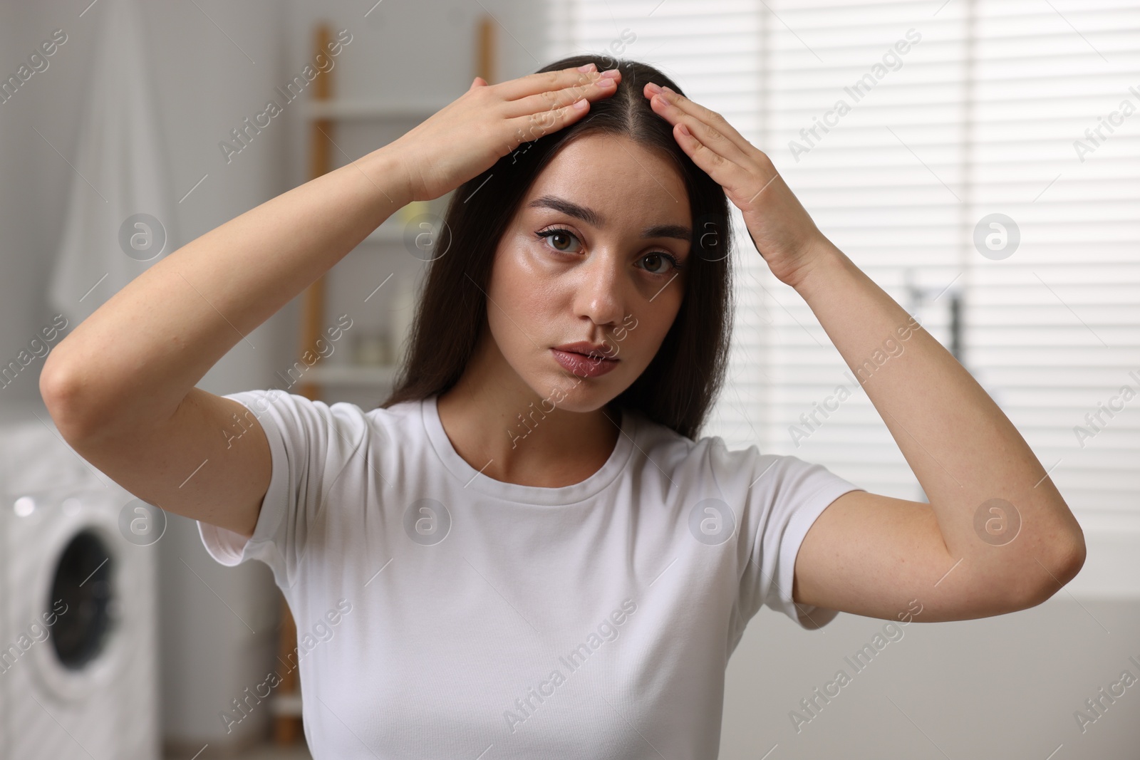 Photo of Woman examining her hair and scalp in bathroom