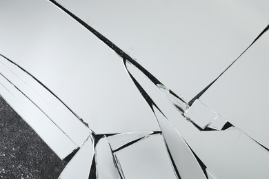 Shards of broken mirror on dark textured background, top view