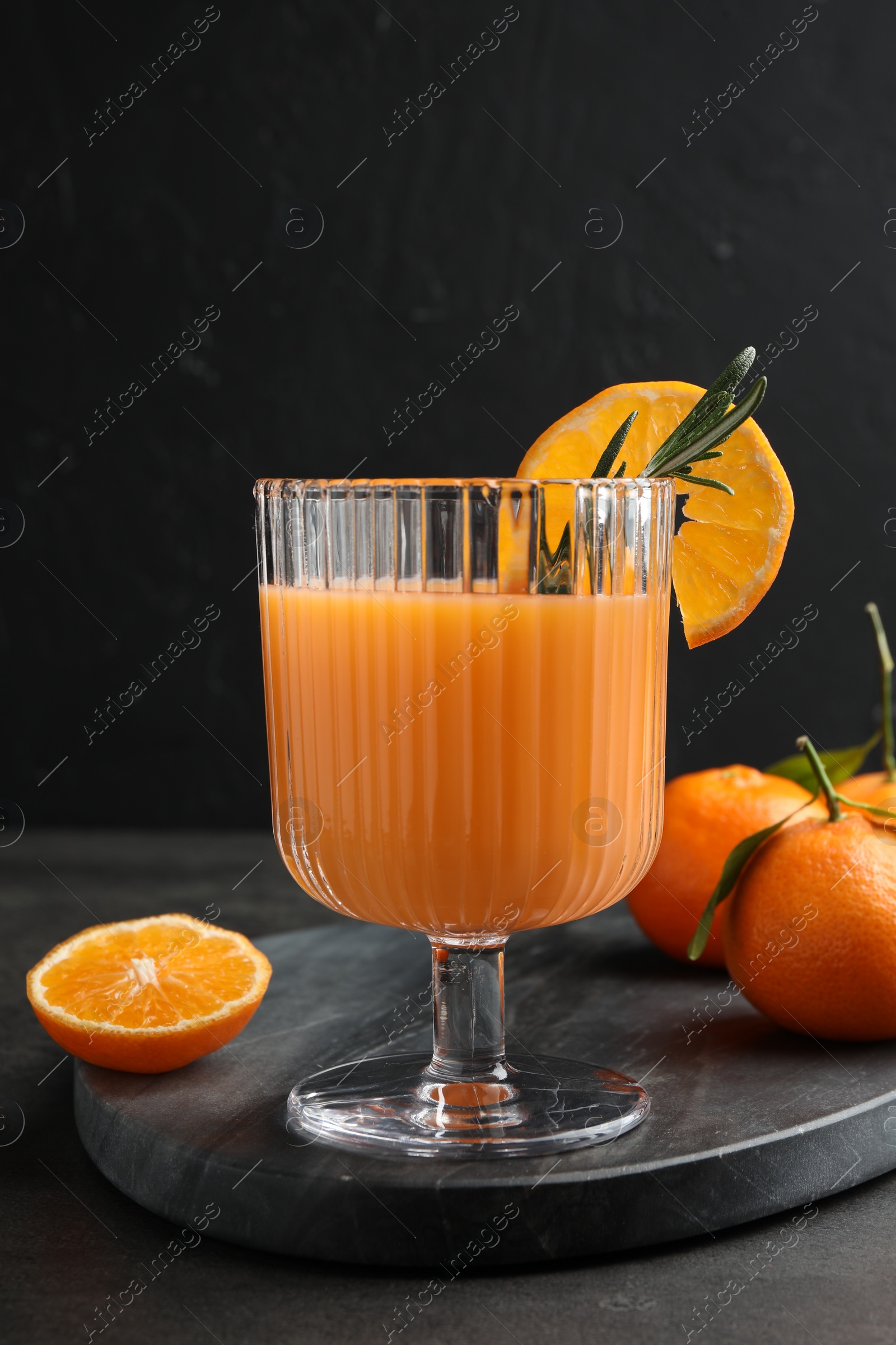 Photo of Delicious tangerine liqueur in glass and fresh fruits on grey table