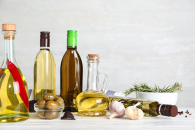 Photo of Composition with different sorts of cooking oil on white wooden table