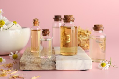 Photo of Aromatherapy. Different essential oils and flowers on pink background