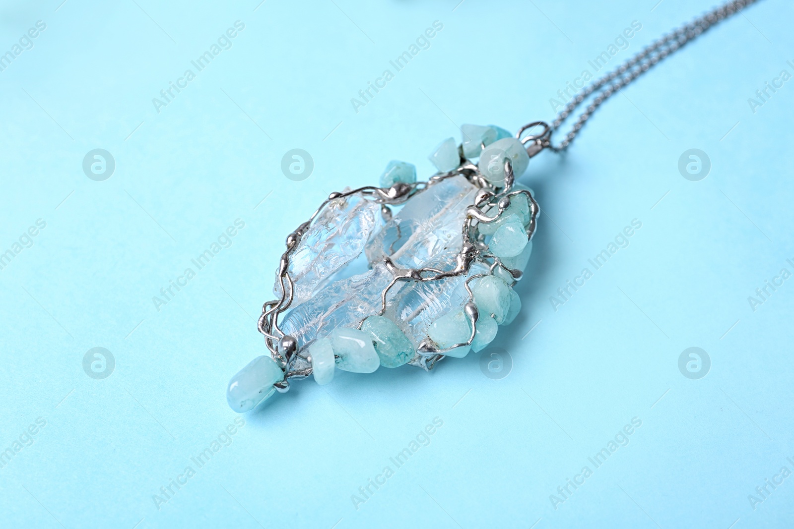 Photo of Beautiful silver necklace with pure quartz gemstones on light blue background