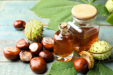 Photo of Chestnuts and essential oil on blue wooden table