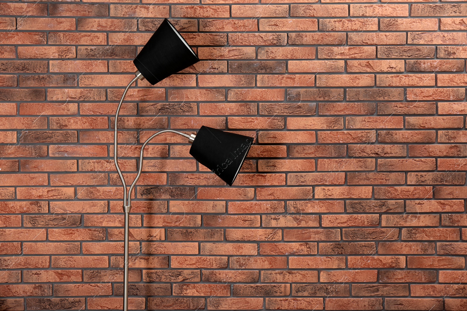 Photo of Stylish lamp near brick wall. Space for text