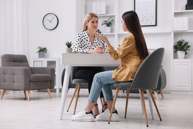 Psychologist working with teenage girl at table in office