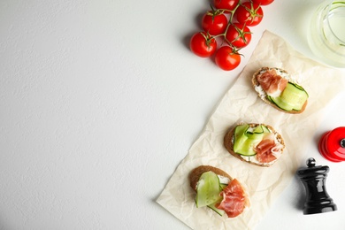 Flat lay composition with delicious bruschettas on white table, space for text