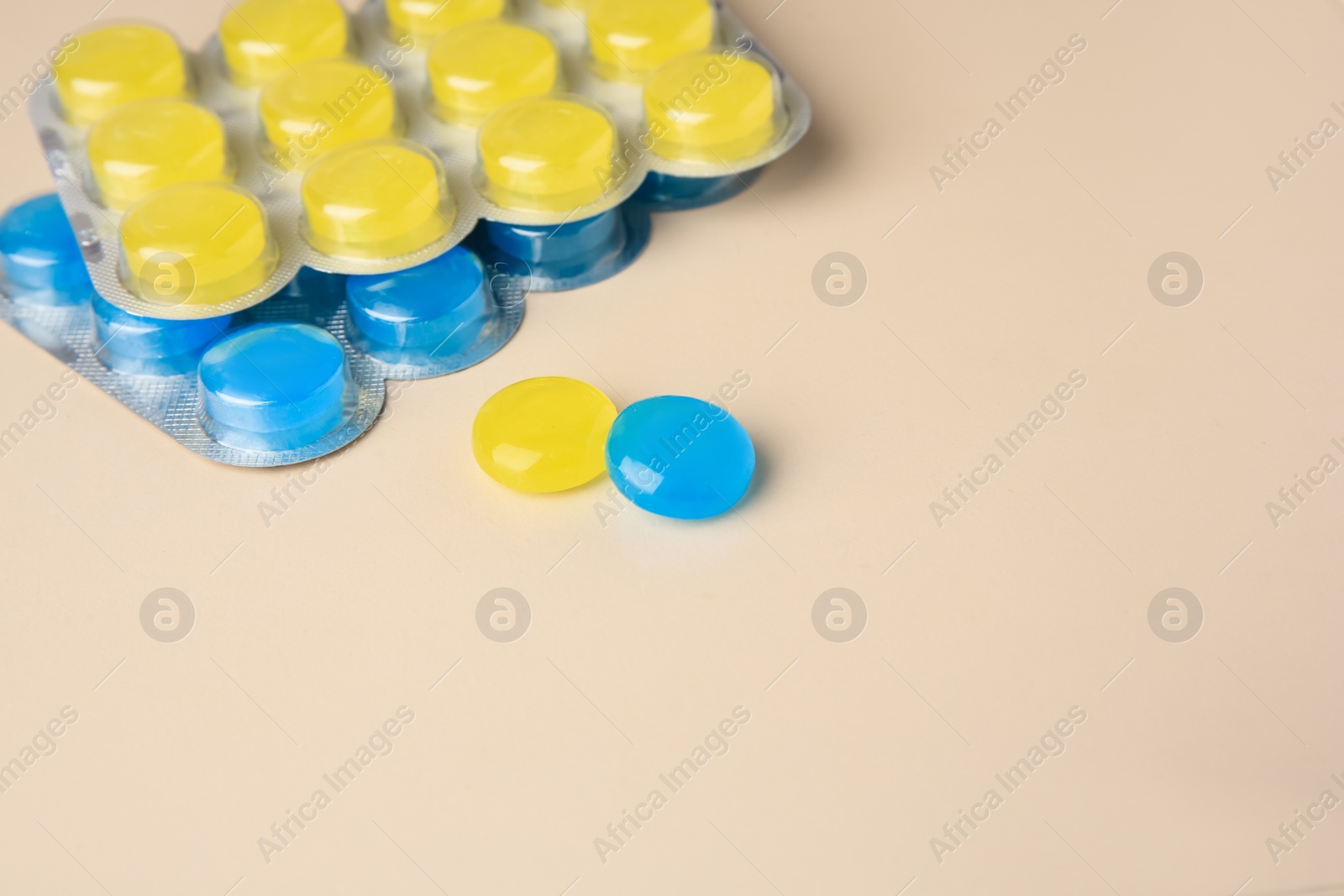 Photo of Blisters with cough drops on beige background, closeup. Space for text