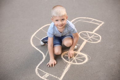 Photo of Little child drawing car with chalk on asphalt