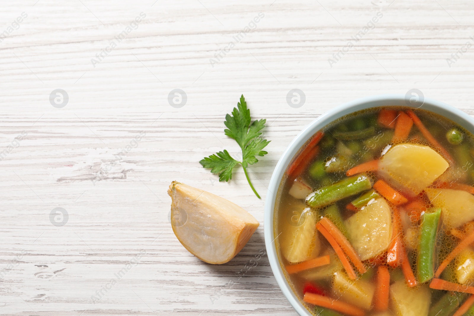 Photo of Bowl of tasty turnip soup on white wooden table, flat lay. Space for text