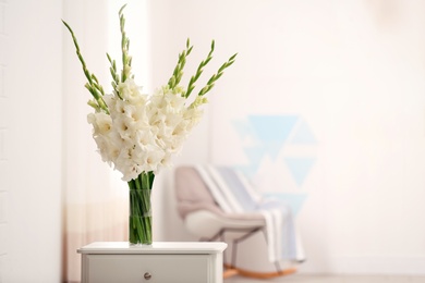 Photo of Vase with beautiful white gladiolus flowers on drawer chest in room, space for text