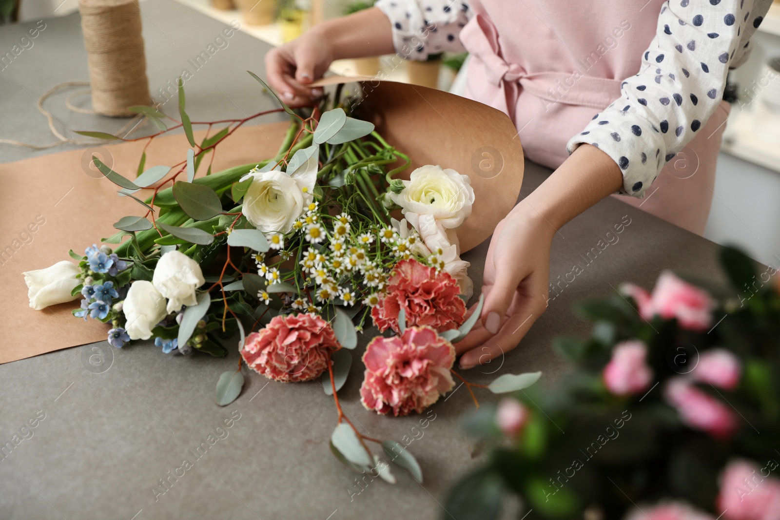 Photo of Florist making bouquet with fresh flowers at table, closeup